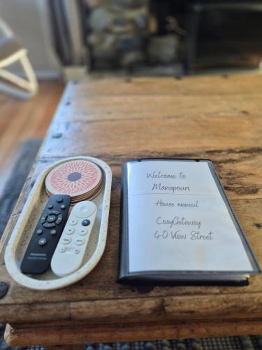 a remote control next to a book on a table at Cosy Getaway 5mins to Doubtful Sound Cruise in Manapouri