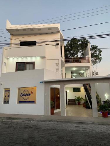 a white building with a sign in front of it at Carpao Lodging Galapagos in Puerto Ayora
