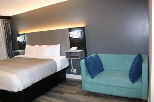 a bedroom with a bed and a blue chair at Quality Inn Bangor Airport in Bangor