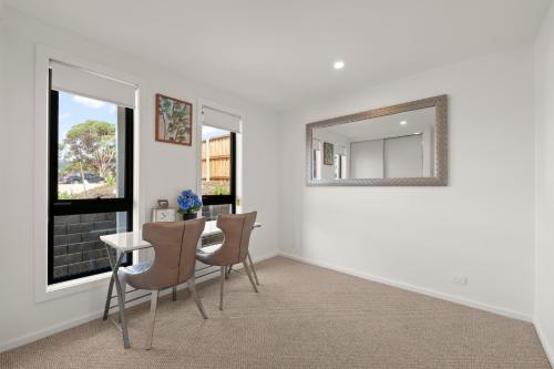 a dining room with a table and chairs and a mirror at Gorgeous 4 Bedroom House - Blackmans Bay in Kingston Beach