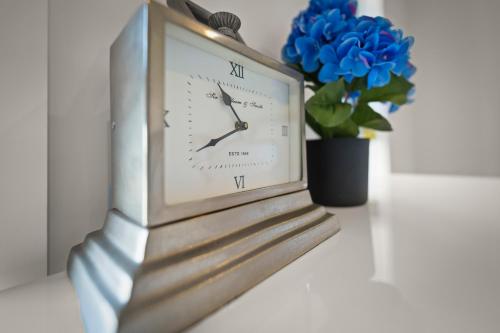 a clock sitting next to a vase with a blue flower at Gorgeous 4 Bedroom House - Blackmans Bay in Kingston Beach