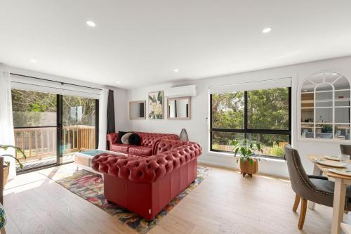 a living room with a red couch and windows at Gorgeous 4 Bedroom House - Blackmans Bay in Kingston Beach