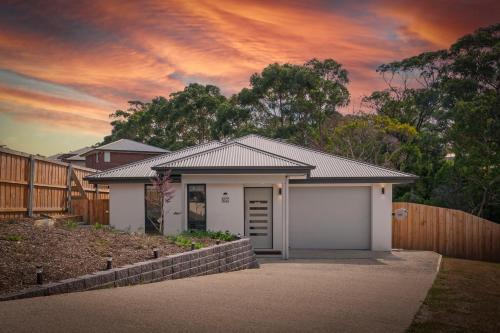 a house with a garage in front of a fence at Gorgeous 4 Bedroom House - Blackmans Bay in Kingston Beach