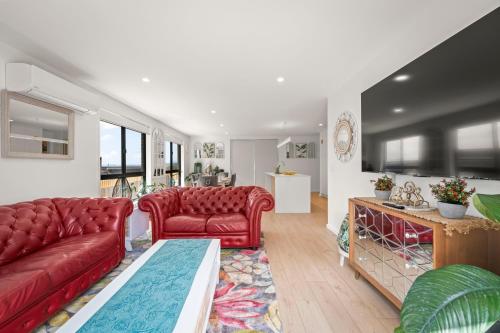 a living room with two red couches and a table at Gorgeous 4 Bedroom House - Blackmans Bay in Kingston Beach
