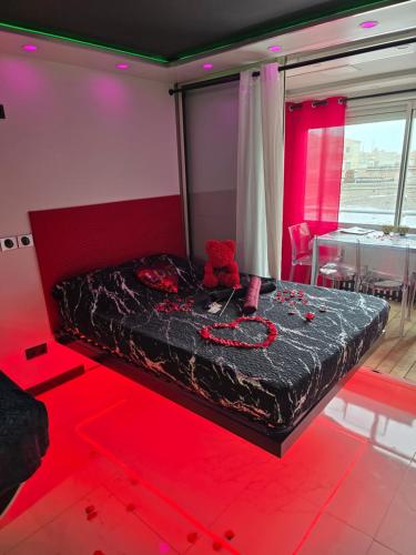 Cette chambre comprend un lit dans une chambre dotée de lumières rouges. dans l'établissement C12 Deluxe, au Cap d'Agde