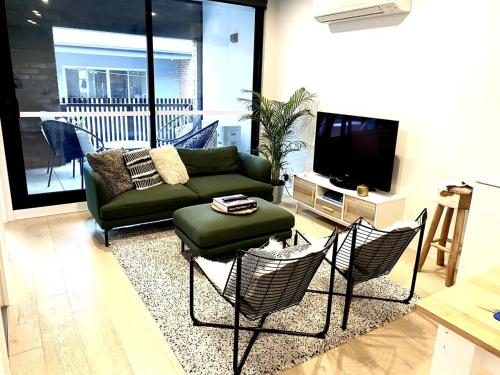 a living room with a couch and chairs and a tv at Modern, stylish 2 bed apartment, great location in Melbourne