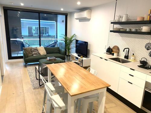 a kitchen and living room with a table and a couch at Modern, stylish 2 bed apartment, great location in Melbourne