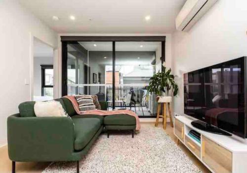 a living room with a green couch and a television at Modern, stylish 2 bed apartment, great location in Melbourne