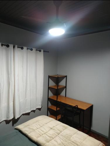 a bedroom with a bed and a desk and a light at Recanto Arvoredo casa 3 quartos piscina garagem e NF para 12 hospedes in Concordia
