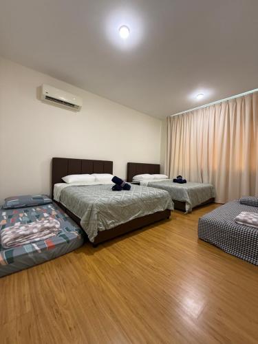 two beds in a room with wooden floors at Riverine Diamond Condominium at City Centre in Kuching