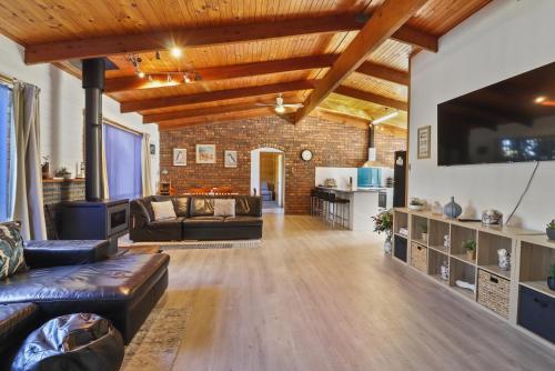 an open living room with a brick wall and wooden ceilings at Ocean Breeze - Sleeps 12 - Pet Friendly in Scamander