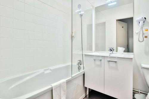 a white bathroom with a shower and a sink at Comfort Aparthotel Toulouse Métropole in Toulouse