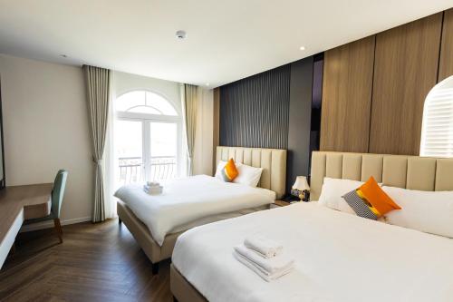 a hotel room with two beds and a window at Luxury Sunset Town Hotel Phu Quoc in Phu Quoc