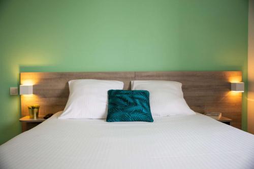 a large white bed with a blue pillow on it at Comfort Aparthotel Toulouse Métropole in Toulouse
