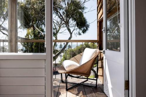 a wicker chair sitting on a porch next to a door at Coastal Tree House- Short Stroll to Beach in Encounter Bay