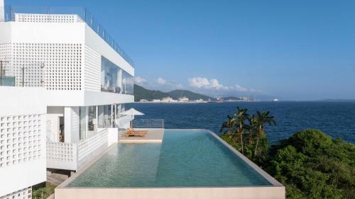a building with a swimming pool next to the ocean at Shenzhen GuanHu Secret Wild Reef Seaview Hotel in Shenzhen