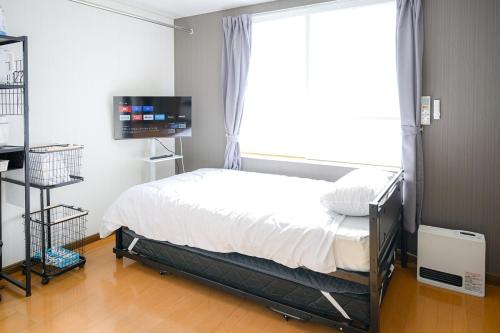 a bedroom with a bed and a window and a television at バンビハイツ長島302 in Aomori