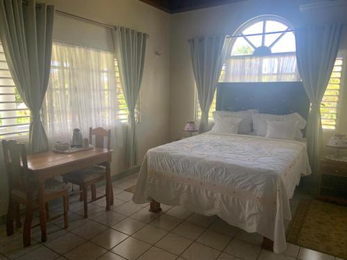 a bedroom with a bed and a desk and a window at Nelsons Retreat in Negril
