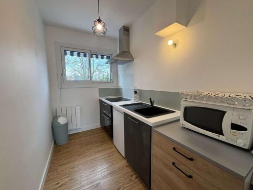 une petite cuisine avec un micro-ondes et un évier dans l'établissement Bel appartement refait à neuf proche plage Royan - FR-1-494-209, à Royan