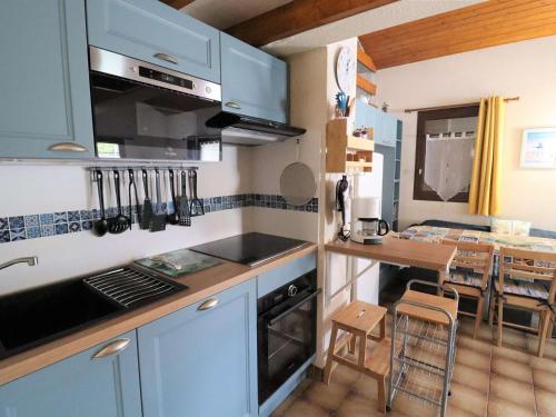 d'une cuisine avec des placards bleus et une table. dans l'établissement Appartement charmant proche plage et parking - FR-1-494-208, à Vaux-sur-Mer