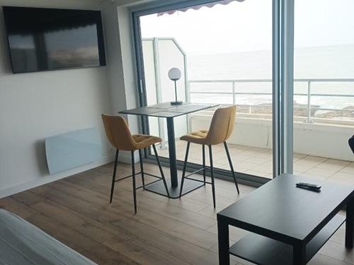 une table et des chaises dans une pièce avec vue sur l'océan dans l'établissement Studio neuf avec terrasse sur mer et garage à Royan - FR-1-494-207, à Royan