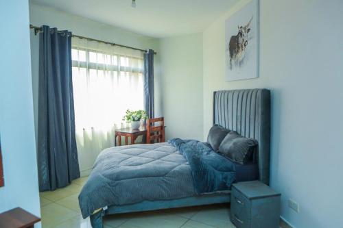 a bedroom with a bed with a blue blanket and a window at Stylish 3-bed Ensuite Apt in Westlands in Nairobi