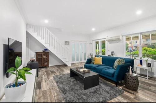 a living room with a blue couch and a staircase at Centre of the Village in Kangaroo Valley