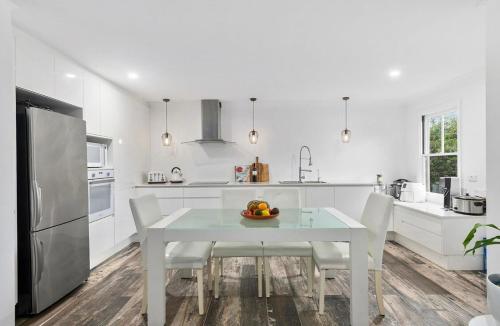 a white kitchen with a white table and chairs at Centre of the Village in Kangaroo Valley