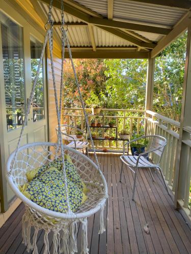a swing on a porch with two chairs at Centre of the Village in Kangaroo Valley
