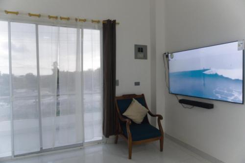 a room with a flat screen tv and a chair at Apartamento Ciudad del Surf Montañita in Montañita