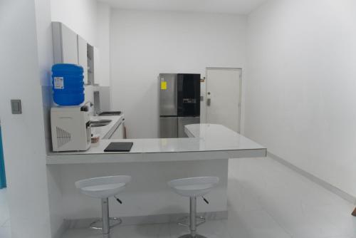 a kitchen with a white counter and stools in it at Apartamento Ciudad del Surf Montañita in Montañita