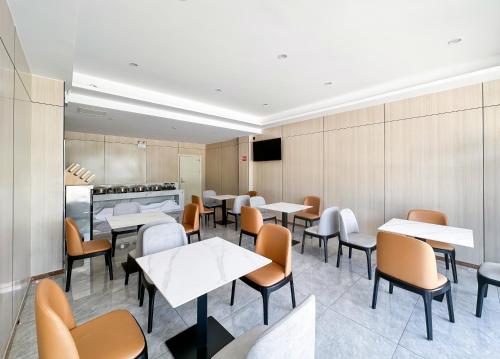 a restaurant with tables and chairs and a kitchen at 沃德 Smart 酒店淄博桓台信誉楼张北路店 in Zibo