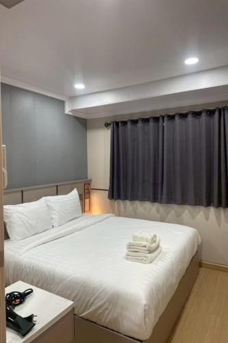 a bedroom with a large white bed and a window at TJ 4711 Residence in Maha Sarakham