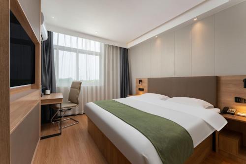 a hotel room with a bed and a desk and a television at 沃德 Smart 酒店淄博桓台信誉楼张北路店 in Zibo