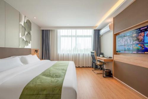 a hotel room with a large bed and a desk at 沃德 Smart 酒店淄博桓台信誉楼张北路店 in Zibo