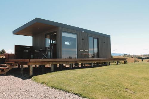 a black house with a wooden deck on a field at Apple Valley West - Mahana in Mahana
