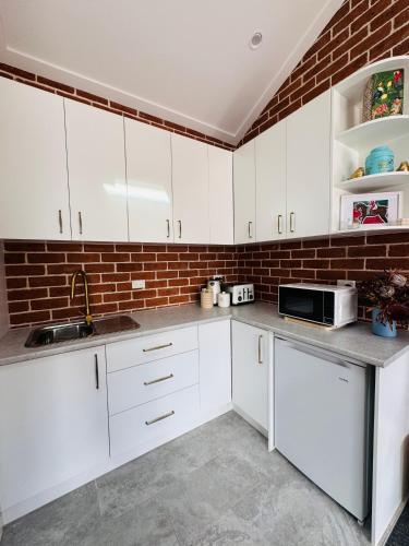 a kitchen with white cabinets and a brick wall at Studio in CBD Bathurst in Bathurst