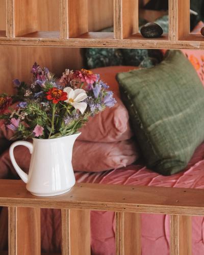 a white vase with flowers in it on a shelf at Apple Valley West - Mahana in Mahana