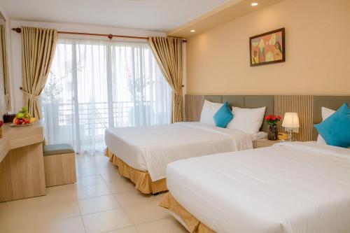 a hotel room with two beds and a balcony at Lanxy Hotel Nha Trang in Nha Trang