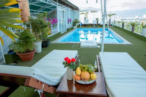 a table with a bowl of fruit on a balcony with a pool at Lanxy Hotel Nha Trang in Nha Trang