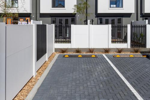 a parking lot in front of a house with a white fence at Upscale Townhouse with Parking in Prime Location in Christchurch