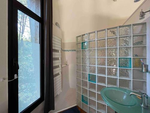 La salle de bains est pourvue d'un lavabo vert et d'une paroi en verre. dans l'établissement Villa Lacanau Evasion, à Lacanau-Océan