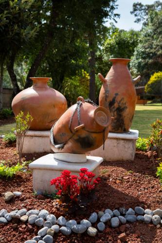three large vases sitting in a garden with flowers at Casa Los Pinos, with a lake view in Avándaro in Valle de Bravo