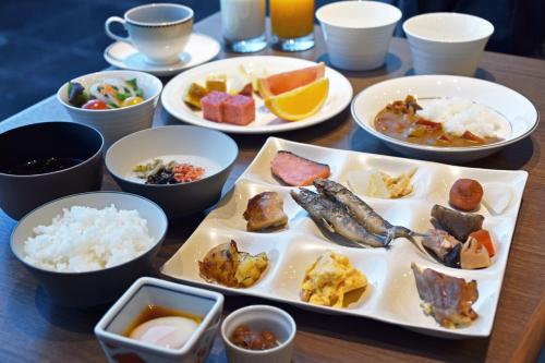 a table with plates of food and bowls of food at Hotel Nikko Tsukuba in Tsukuba
