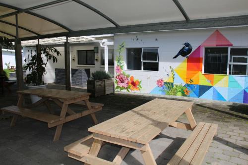 a picnic table and benches in front of a house at Pakiri Beach Holiday Park in Pakiri