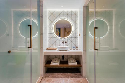 a bathroom with a sink and two mirrors at Huayang Hotel Century City Convention and Exhibition Center Branch in Zhongxingchang
