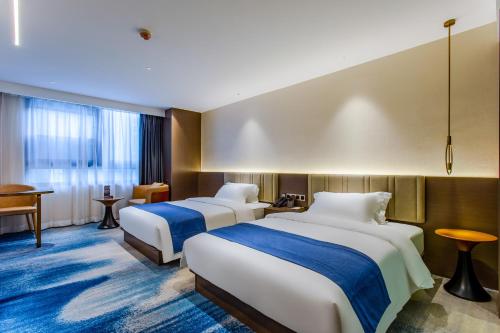 a hotel room with two beds and a table at Huayang Hotel Century City Convention and Exhibition Center Branch in Zhongxingchang