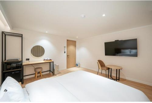 a bedroom with a large white bed and a desk at Brown Dot Hotel South Gumi in Yangji-mal