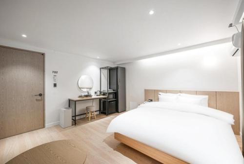 a bedroom with a large white bed and a desk at Brown Dot Hotel South Gumi in Yangji-mal