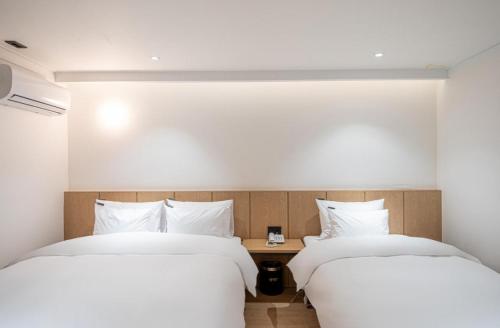 two beds in a hotel room with white sheets at Brown Dot Hotel South Gumi in Yangji-mal